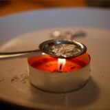 Bleigießen: Löffel mit geschmolzenem Blei über einem Teelicht