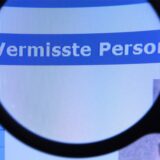 Eine Lupe vor einem Computermonitor, die die Worte „Vermisste Person“ vergrößert.
