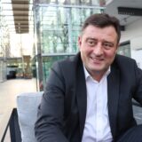 Mathias Richter sitzt mit Sakko und Hemd im Foyer des Ruhrfestspielhauses Recklinghausen.