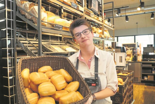 Eine Bäckereiverkäuferin steht in einer Bäckerei in Datteln und hält einen Korb mit Brötchen in den Händen. (Archivbild)