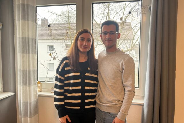 Eine Frau und ein Mann stehen in einem Wohnzimmer in ihrer Wohnung in Datteln. Sie stehen vor einer Fensterscheibe, an der eine Kette mit Sternen hängt.