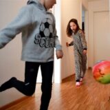 Zwei Kinder spielen in einer Wohnung mit einem Ball.