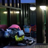 Unter dem Vordach der Volkshochschule liegen hinter zwei Säulen Schlafsäcke und Einkaufswagen voller Hab und Gut.