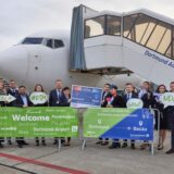 Auf dem Rollfeld des Dortmunder Flughafens posieren vor einem Flugzeug Mitarbeiter aus Dortmund und Rumänien. Vor ihnen stehen Banner mit der Aufschrift: Willkommen, Dortmund, Bacău, jetzt mit Dan Air.