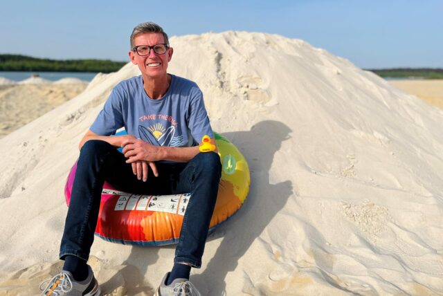 Ein Mann sitzt auf einem Sandhaufen am Silbersee