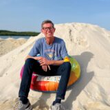Ein Mann sitzt auf einem Sandhaufen am Silbersee