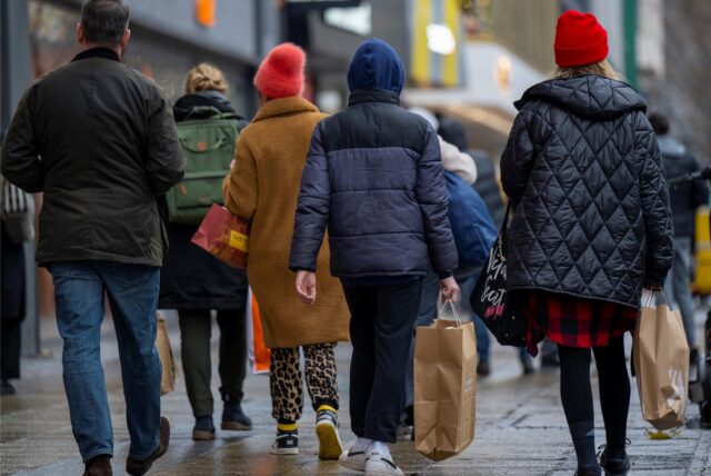 Menschen sind mit Einkaufstaschen in der Innenstadt einkaufen.