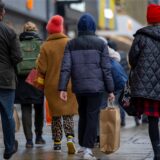 Menschen sind mit Einkaufstaschen in der Innenstadt einkaufen.