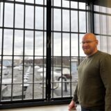 Ein Gefangener der JVA Schwerte steht vor einem vergitterten Fenster.