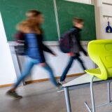 Schüler gehen nach Unterrichtsschluss aus einem leeren Klassenzimmer.