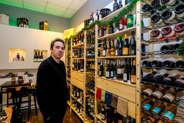Pascal Hermeler steht in seinem Weinhandel „The Tasting Room“ in Recklinghausen vor einem gefüllten Weinregal.