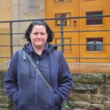 Frau steht vor einer Treppe, die zu der Tür eines Gebäudes führt.