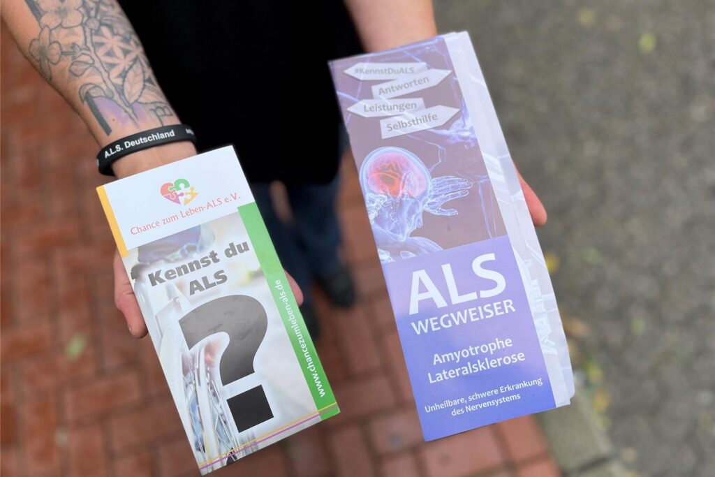 Zwei Hände halten zwei Aufklärungsflyer zur Erkrankung ALS Zwei Hände halten zwei Aufklärungsflyer zur Erkrankung ALS