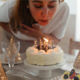 Eine Frau pustet die Kerzen auf einer Geburtstagstorte aus.