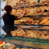 Eine Frau nimmt ein Brot aus einem Regal in einer Bäckerei.
