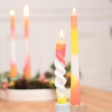 Zwei bunte Kerzen stehen auf einem Tisch.