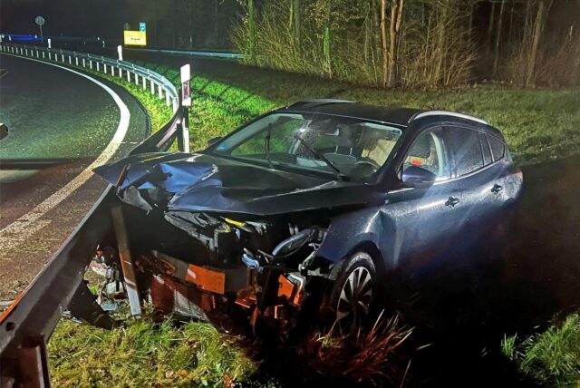 Ein im Frontbereich zerstörtes Auto steht an einer Leitplanke.