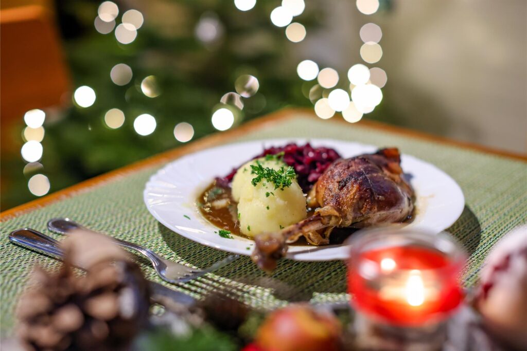 Eine Portion Gänsekeule mit Rotkraut und Klößen steht an Weihnachten auf einem Tisch. Eine Portion Gänsekeule mit Rotkraut und Klößen steht an Weihnachten auf einem Tisch.