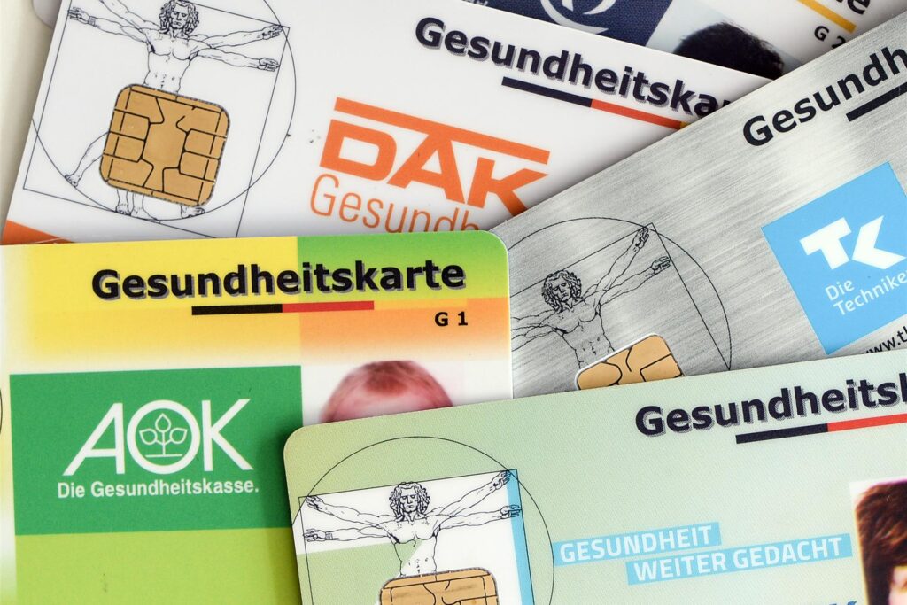 Gesundheitskarten verschiedener Krankenkassen liegen auf einem Tisch.