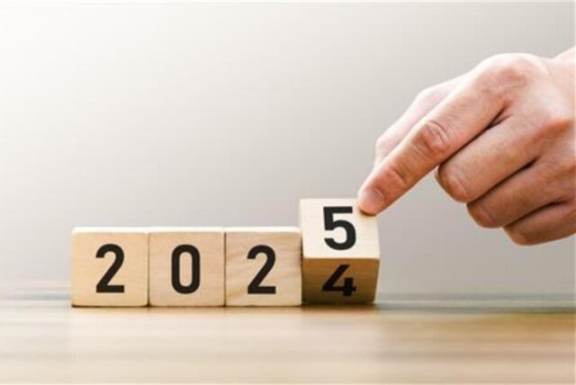 Eine Hand dreht einen von vier Würfeln um, sodass aus 2024 die Jahreszahl 2025 wird.