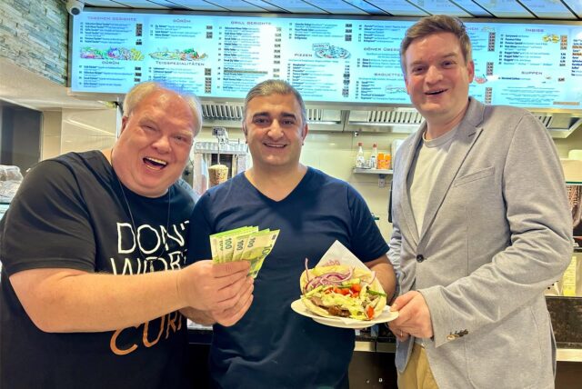 Thomas Frauendienst überreicht die ersten Hundert-Euro-Scheine an Selam Tasdemir, während sich Michael Breilmann von der Döner-Qulität überzeugt.