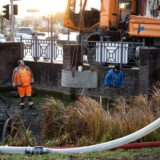 Mitarbeiter des Dorstener Entsorgungsbetriebes stehen in der Wall- und Grabenanlage. Mit einem Kran heben sie die neue Pumpe in Position.