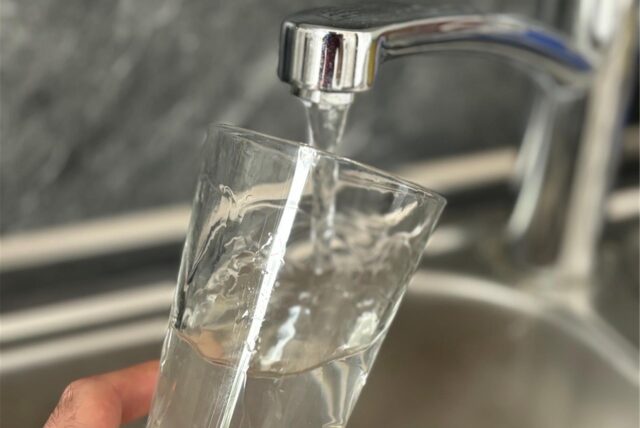 Wasser fließt aus dem Wasserhahn in ein Glas