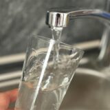 Wasser fließt aus dem Wasserhahn in ein Glas