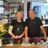 Ex-BVB-Spieler Giuseppe „Billy“ Reina und seine Frau Julia haben das Bistro SiSi auf der Massener Str. 21 in Unna eröffnet. Die beiden neuen Inhaber stehen gemeinsam hinter der Theke neben einem Blumenstrauß und lächeln.