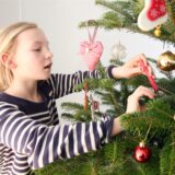 Die zehnjährige Josefine schmückt einen Weihnachtsbaum