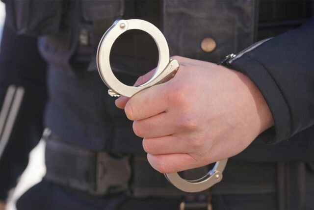 Ein Polizist hält Handschellen in der Hand.