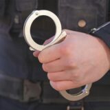 Ein Polizist hält Handschellen in der Hand.