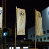 Mehrere wehende Fahnen mit dem VW-Logo vor einem Gebäude mit dem VW-Logo.