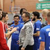 Bei einem Fußball-Hallenturnier versammelt sich eine Traube aus Spielern und Offiziellen um den Schiedsrichter.