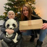 Conner aus Marl und seine Mutter hocken vor einem Weihnachtsbaum und halten Geschenke aus einer Spendenaktion in den Händen.