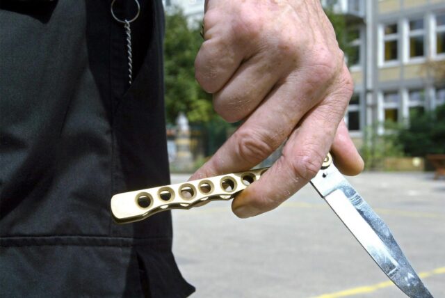 Eine Hand hält ein halb ausgeklapptes Butterfly-Messer fest.