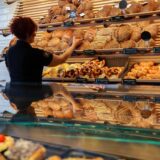 Eine Frau räumt in einer Bäckerei Backwaren in die Auslage.