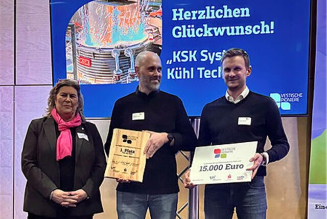 Eine Frau und zwei Männer stehen auf einer Bühne und halten Schecks hoch