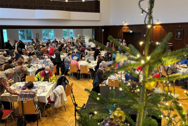 Weihnachtsbaum, im Hintergrund Teilnehmer an der Feier im Wichernhaus.