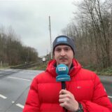 Ein Reporter steht mit einem Mikrofon in der Hand an einem Bahngleis in Dortmund-Kirchderne.