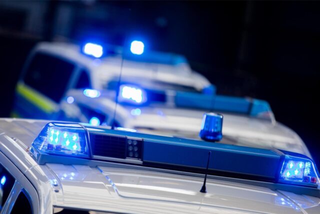 Drei Polizeifahrzeuge mit eingeschaltetem Blaulicht.