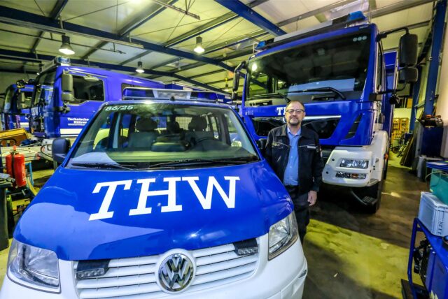 Die Aufnahme von Januar 2022 zeigt den damaligen Ortsbeauftragten des THW Recklinghausen Ulrich Mühlenbeck zwischen blau-weißen Fahrzeugen in der voll gestellten Fuhrparkhalle an der Carl-Still-Straße. (Archivbild)