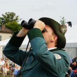 Ein Schütze beobachtet mit einem Fernglas das Vogelschießen des Bürger- und Schützenvereins Oberwiese.
