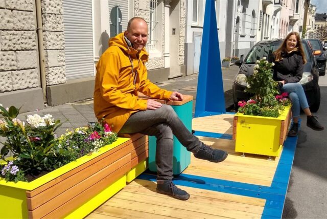 Ein Mann und eine Frau sitzen auf sogenannten Stadtmöbeln.