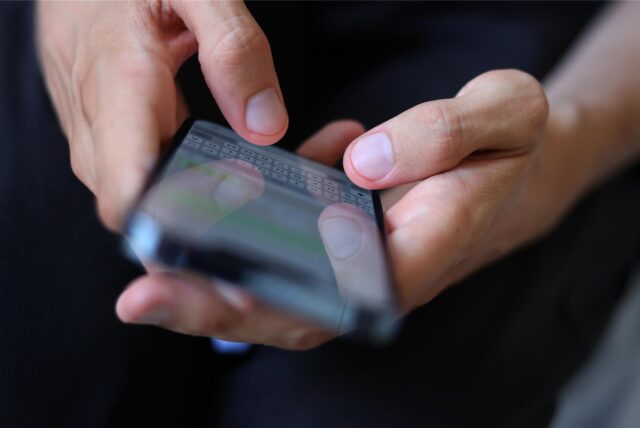 Ein Mann hält ein Handy in der Hand und tippt eine Nachricht.