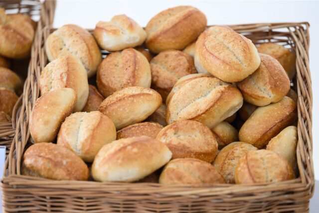 Ein Korb mit Brötchen steht in einer Bäckerei auf einem Tisch.