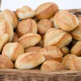 Ein Korb mit Brötchen steht in einer Bäckerei auf einem Tisch.