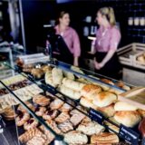 Symbolbild: Zwei Verkäuferinnen in roten Blusen stehen hinter der Auslage einer Bäckerei.