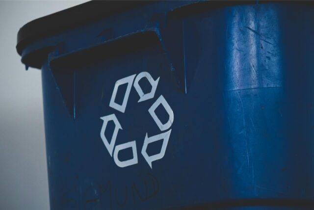 Aufnahme einer blauen Tonne mit einem Recyclingsymbol darauf.