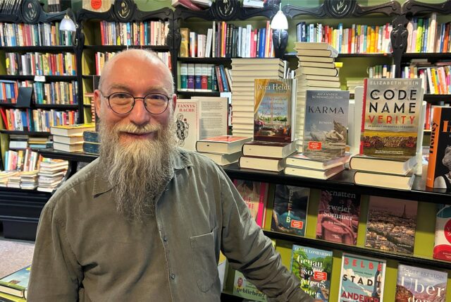 Wolfgang Tänzer steht vor einem Bücherregal in seiner Buchhandlung Bücherwurm.